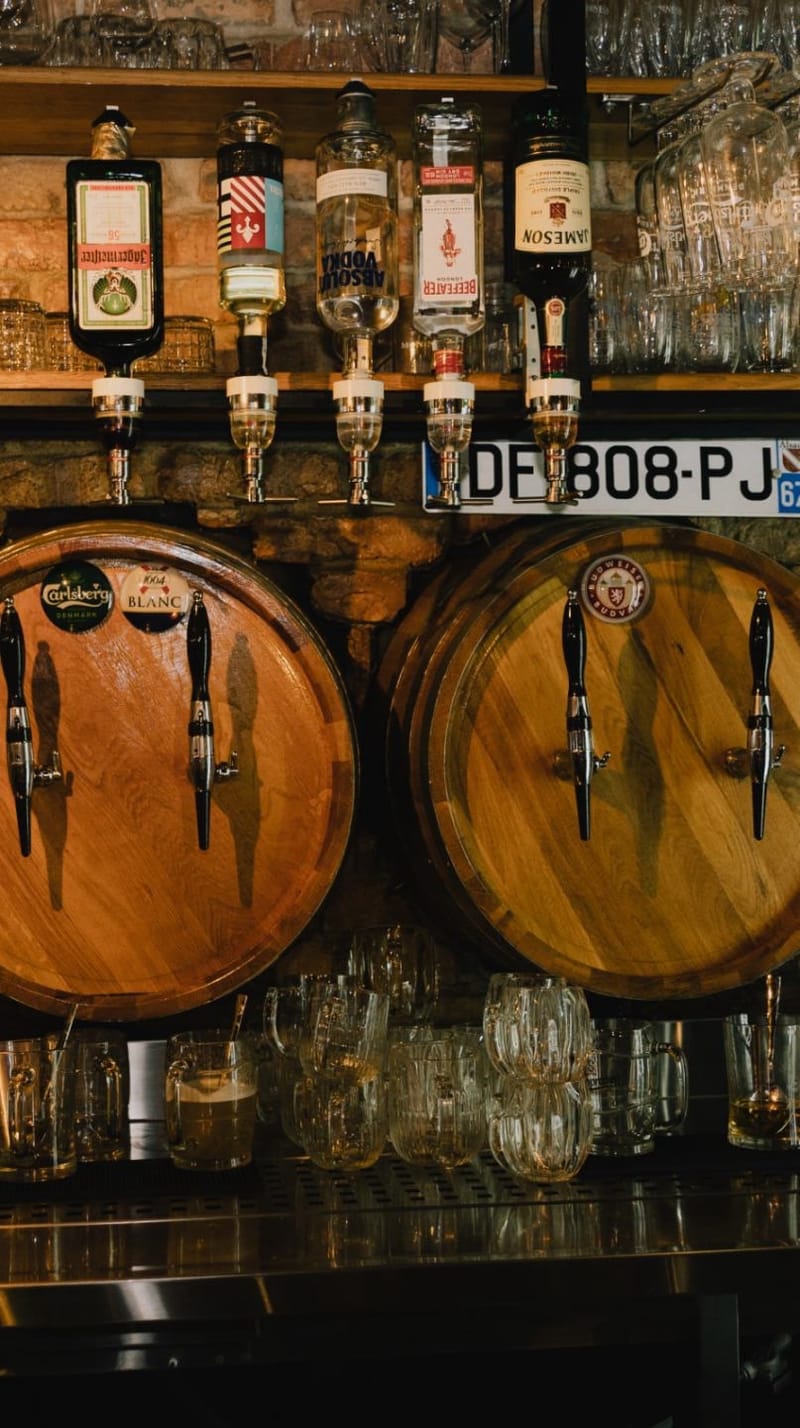 Šank Pub Arke: točionici na drvenim bačvama, a iznad njih boce na dozatorima.