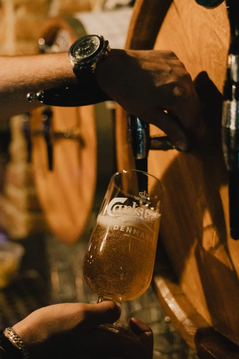 Konobar toči hladno pivo iz točionika na drvenoj bačvi u čašu.